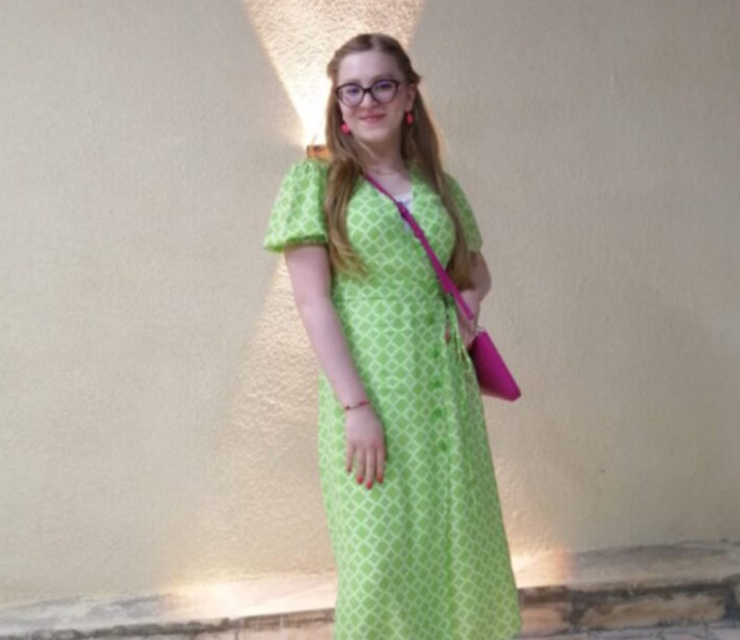 A young woman wearing a green dress poses for the camera.